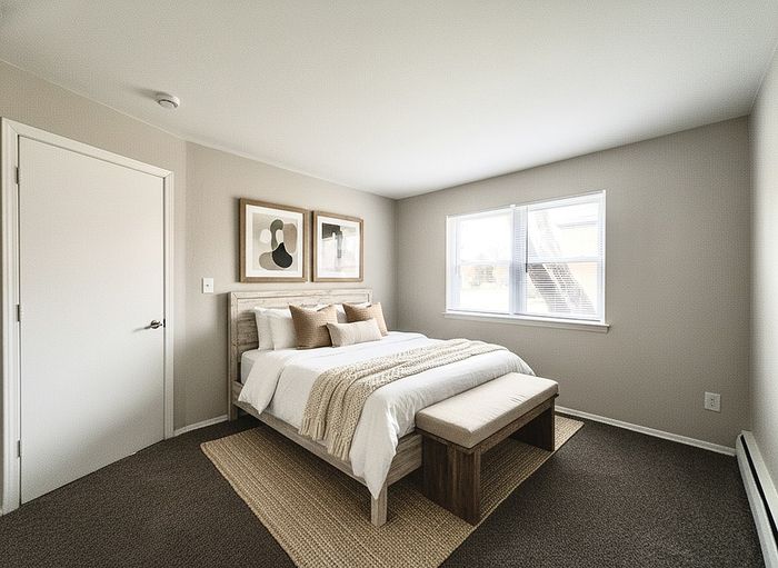 Elegant bedroom showcasing modern decor with plush bedding, cozy earth-toned accents, and ample natural light from a large window.