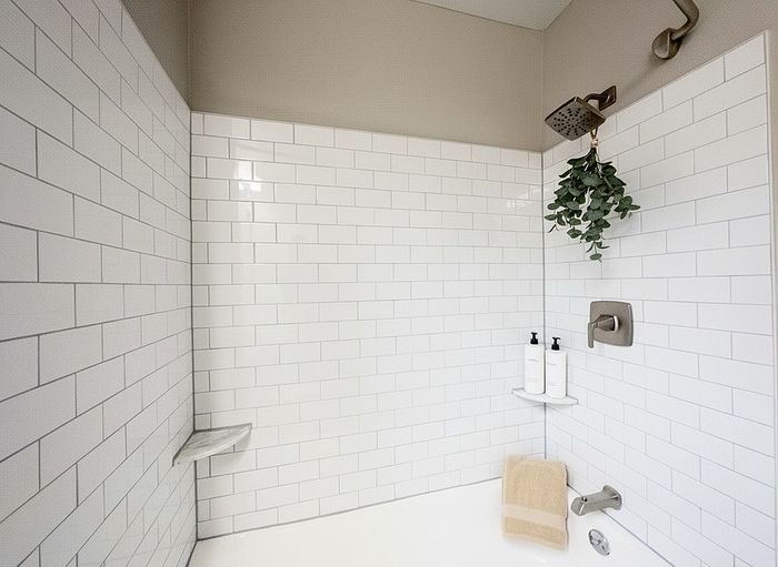 Elegant bathroom featuring classic white subway tiles, modern showerhead, and stylish greenery for a refreshing ambiance.