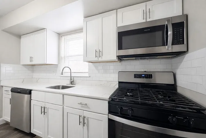 Modern kitchen featuring sleek stainless steel appliances, elegant white cabinetry, and a polished marble countertop.