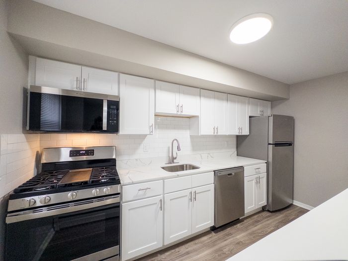 Modern kitchen with sleek stainless steel appliances, bright white cabinetry, and elegant stone countertops.