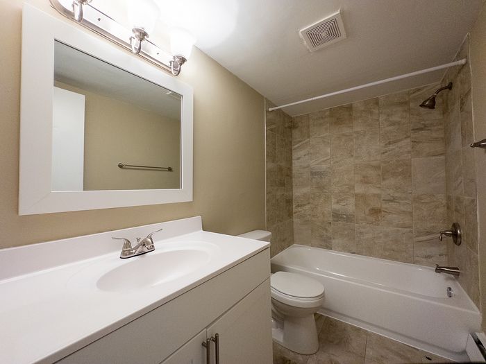 Elegant bathroom with modern fixtures, featuring a sleek vanity, large mirror, and a tiled shower area with a bathtub.