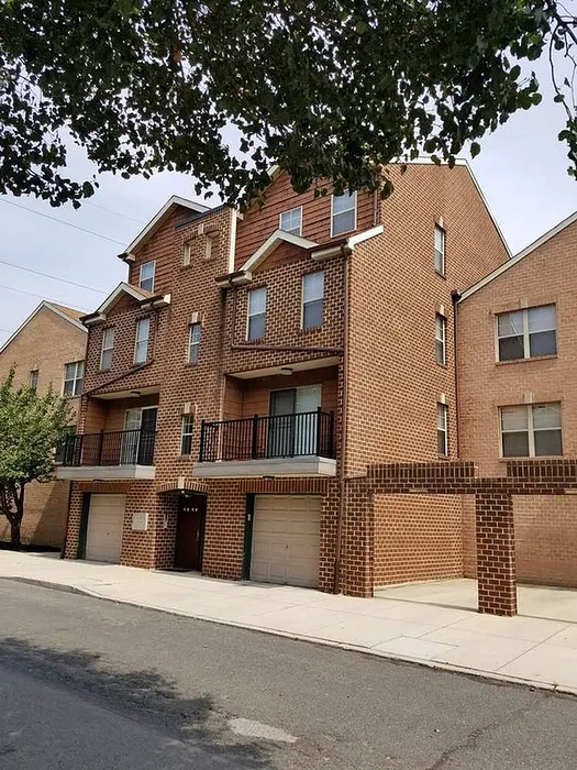 Charming multi-level brick apartment building with modern balconies and a tree-lined street.