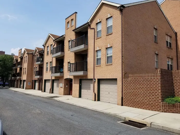 Charming brick townhouse complex with private balconies overlooking a quiet street, offering modern urban living.