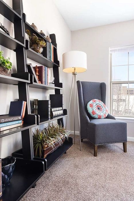 Elegant living space with a modern bookshelf, plush armchair, and a bright window view, perfect for relaxation and inspiration.