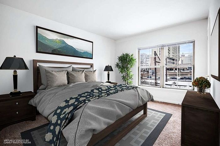 Bright and inviting bedroom with a cozy bed, stylish decor, and large window offering a city view.