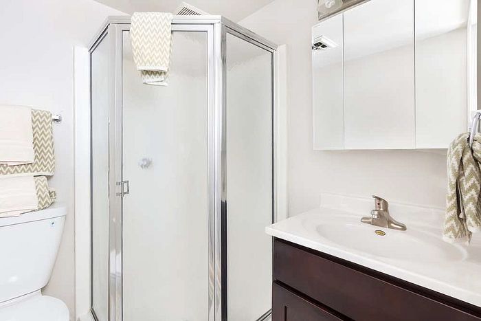 Modern bathroom with sleek glass shower, elegant vanity, and chic chevron towels.