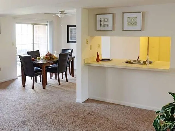 Bright open-concept living area with cozy dining space, modern kitchen pass-through, and elegant decor, perfect for entertaining.