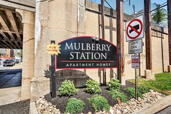 Eye-catching sign for Mulberry Station Apartment Homes, showcasing vibrant landscaping and convenient urban location.