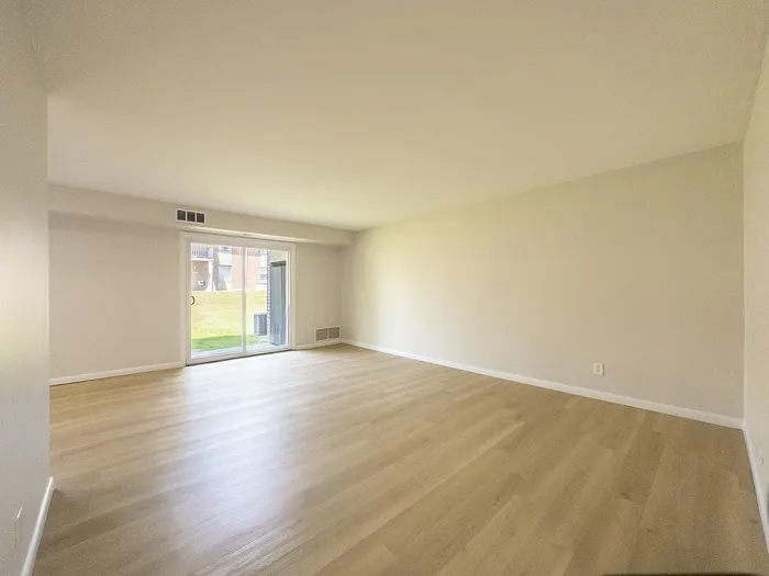 Spacious living room featuring elegant wood flooring and a large window offering abundant natural light.
