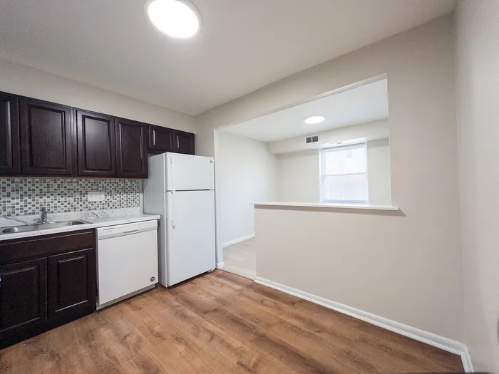 Modern kitchen with sleek dark cabinets, elegant backsplash, and spacious layout featuring bright natural light.