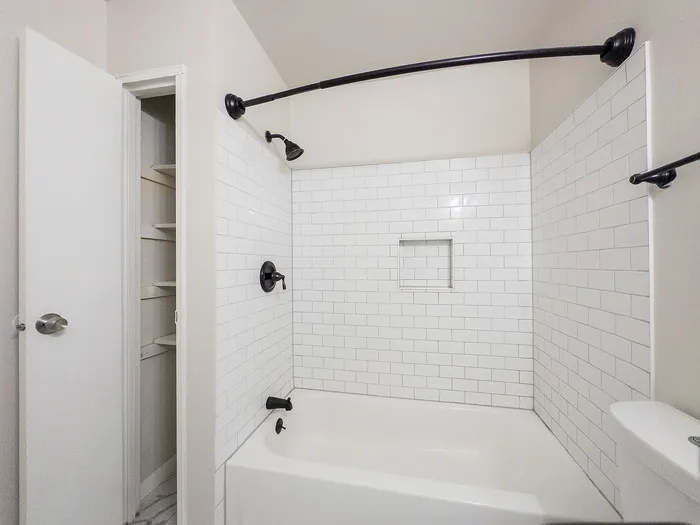 Chic bathroom featuring a modern white subway tile design, spacious bathtub, and elegant black fixtures.