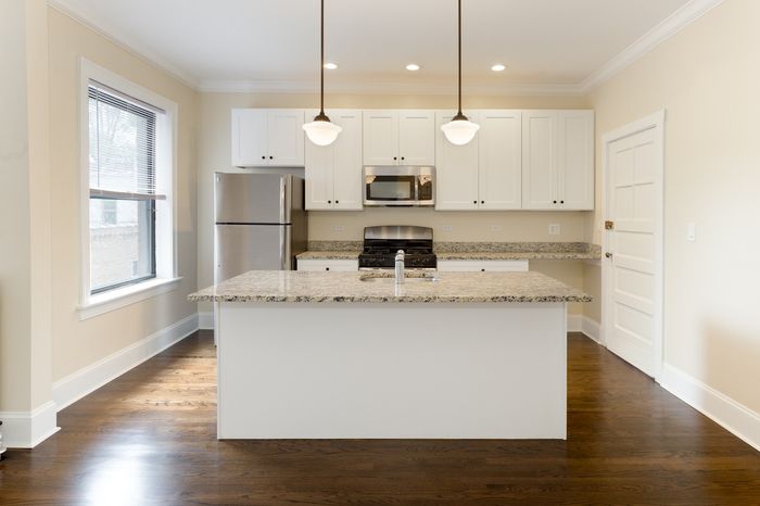 A kitchen with an open concept floor plan, pendant lights, granite tops, and stainless steel appliances including a dishwasher.