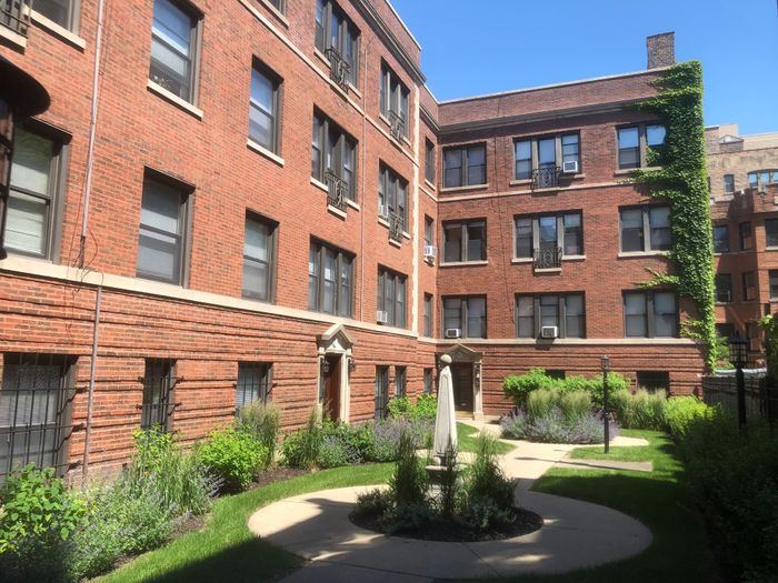 Exterior of 1360-64 East 52nd Street a handsome twenty two unit 3.5 story red brick courtyard building on a tree lined street in Hyde Park.