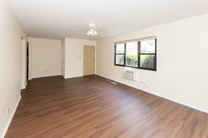 Living room with air conditioner and vinyl wood flooring.