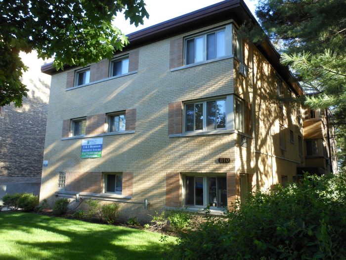 Exterior of 810 Seward an eleven unit three story mid century yellow brick building on a tree lined street in Evanston.
