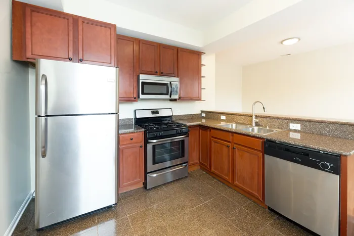 A kitchen with an open concept layout, wooden cabinets, stainless appliances, granite tops, and a dishwasher.