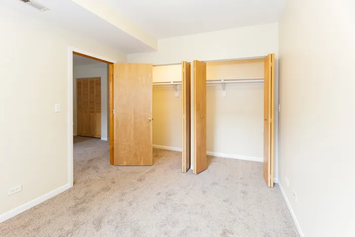 A bedroom with two large closets equipped with wire shelving.