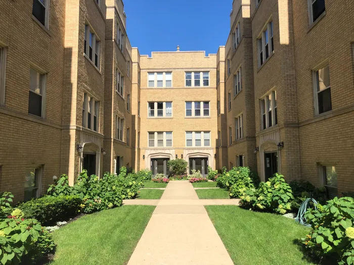 Exterior of 1118-28 East Hyde Park Boulevard a handsome thirty seven unit 3.5 story yellow brick courtyard building with landscaped courtyard in Hyde Park.