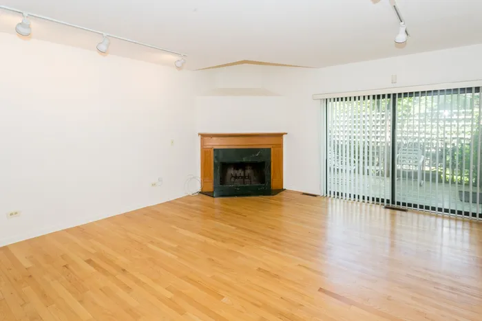 Living room with fireplace, light hardwood floors, and a sliding glass door.