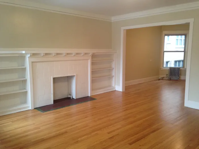 A living room with a decorative fireplace, light hardwood floors, and a neutral color palette.
