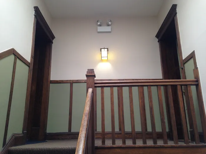 The nicely decorated front staircase with green and light beige walls, and dark wooden doors.