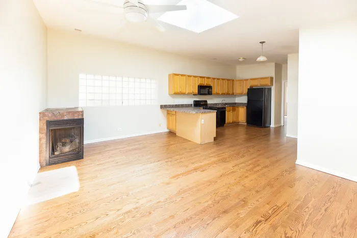 Kitchen and living rooms are combined.  With light hardwood floors, a fireplace, skylight, and ceiling fan.