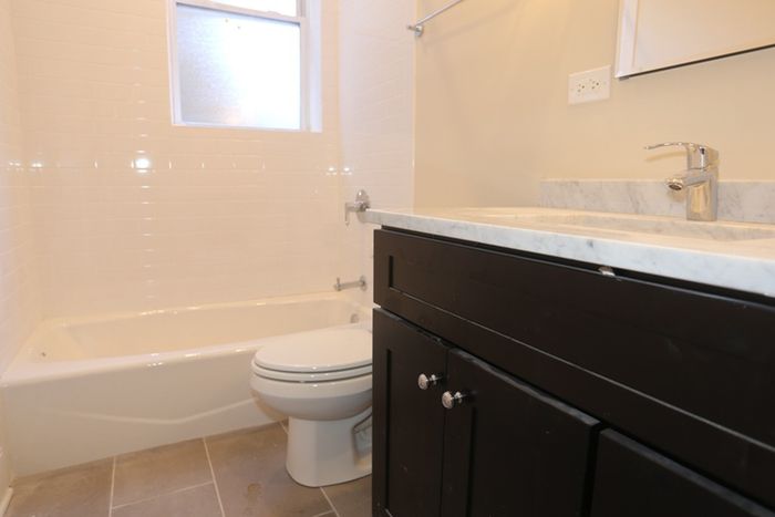 Renovated bathroom with an ebony vanity, grey granite top, and a white bathtub.