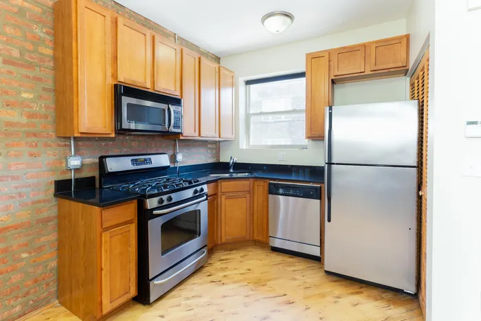 A kitchen with light wooden cabinets and stainless steel appliances including a dishwasher.