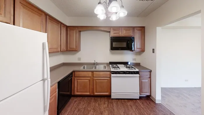 A kitchen with wood cabinets, a gas stove, dishwasher, and stainless sink.