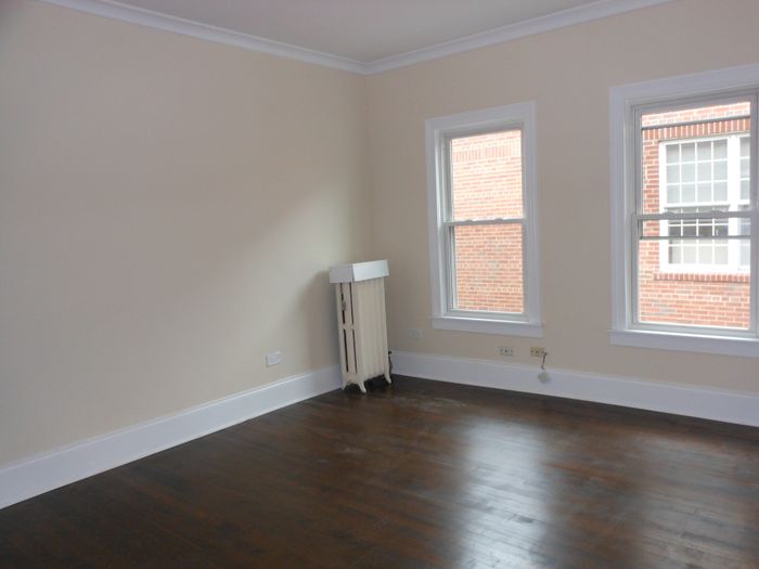 Bright and sunny living room with dark hardwood floors and off white walls.