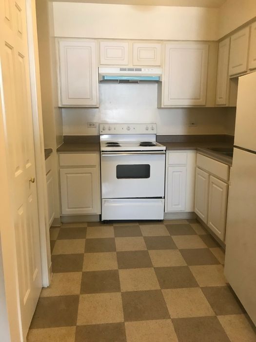 Kitchen with white cabinets, a checkered floor, and an electric stove.