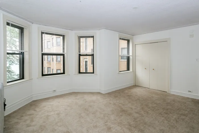 Bright and sunny living room with a courtyard view and wall to wall carpeting.