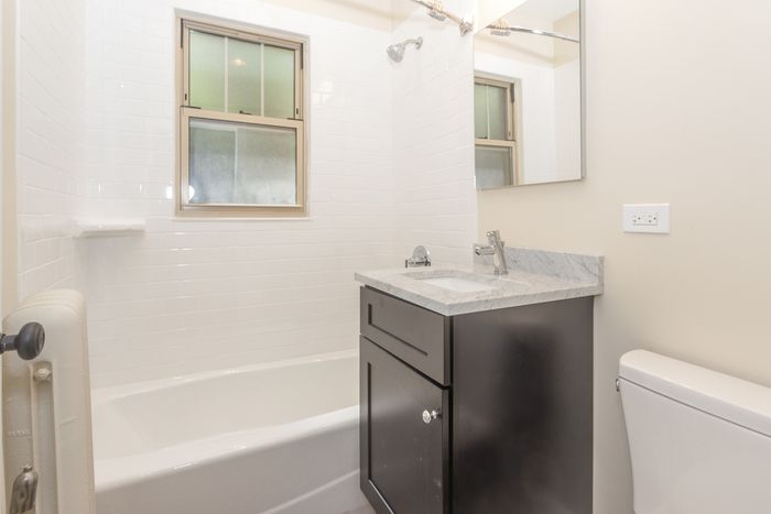A junior one bedroom bathroom with an ebony vanity, grey granite top, and white bathtub.