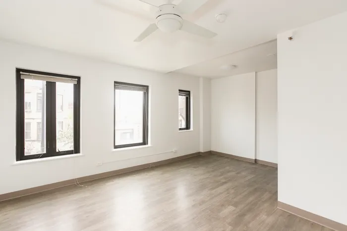 A living room with large bright windows a celling fan