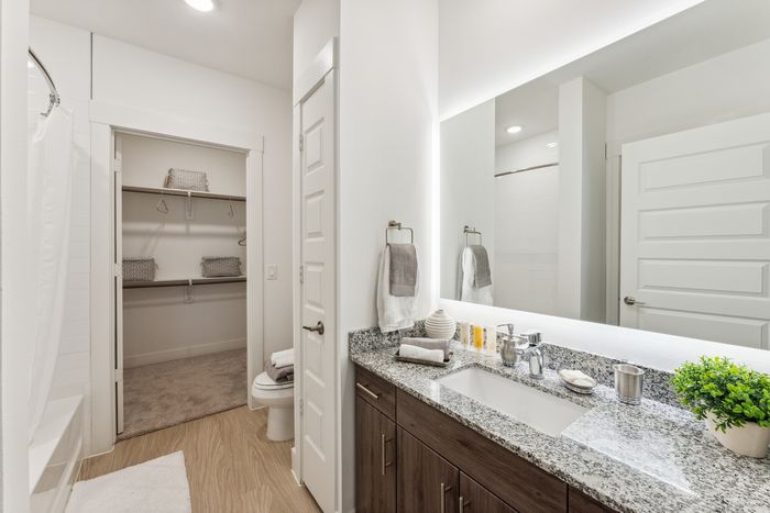 Modern bathroom with tall ceilings, a walk-in closet, bath and shower combination, and a large mirror