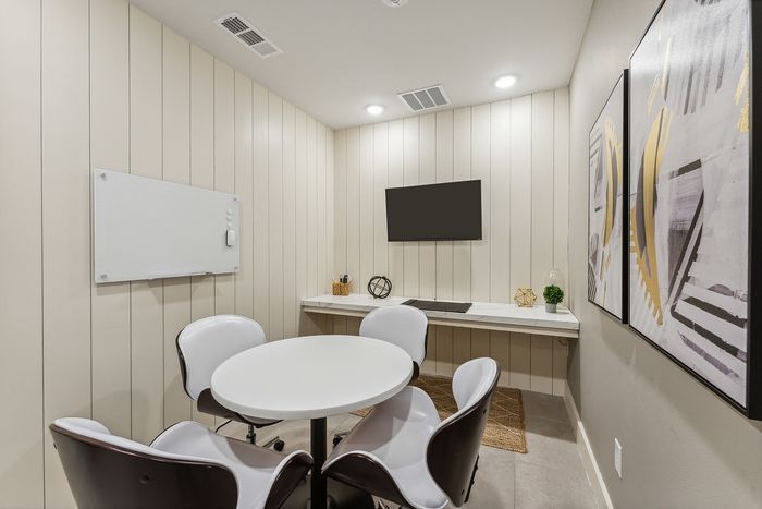 Cozy office space with a white board, television, table, and chairs
