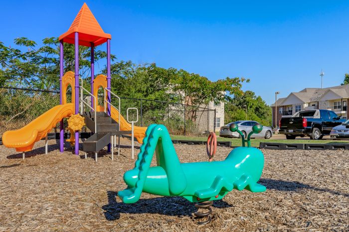 Southwest Pines Playground in Tyler, TX, with children climbing and sliding on outdoor play equipment.