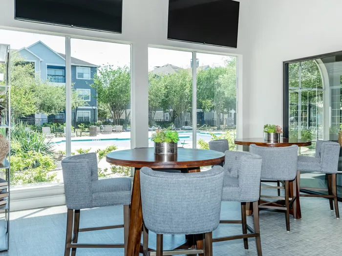 clubhouse dining area with comfortable seating, large windows, and televisions