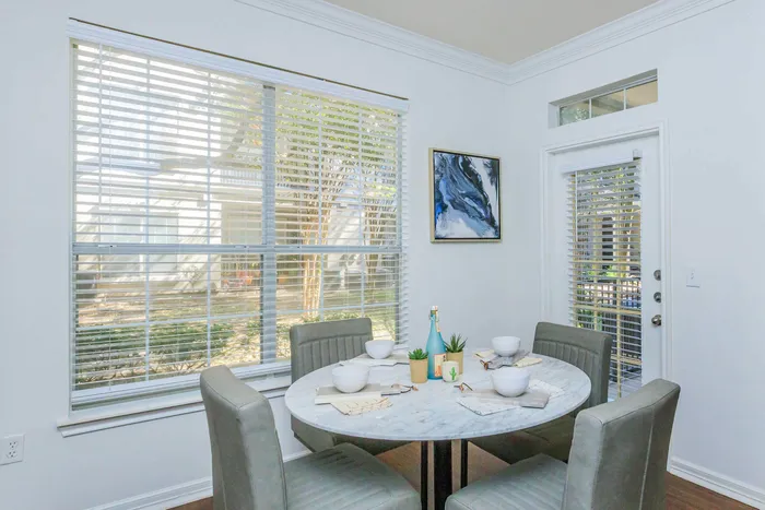 dining room space with a large window letting in natural light that lands on a large dining table