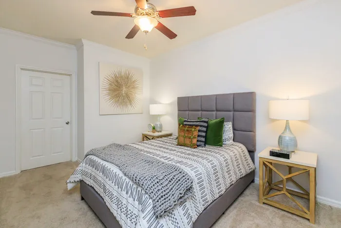 modern bedroom with a comfortable bed, night stands, wall-to-wall carpet, and a ceiling fan