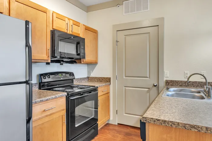 Contemporary kitchen with stainless steel appliances and granite countertops at Riverside at Rockwater, North Little Rock, AR