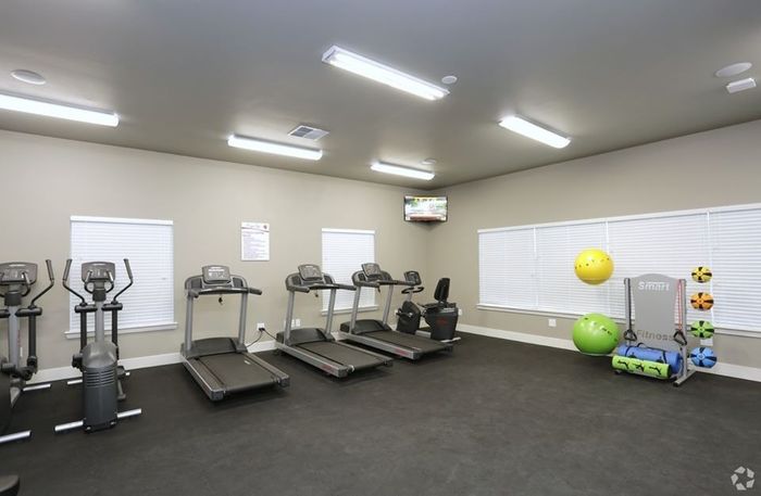 Cardio and strength training equipment in a spacious fitness center at Arroyo Seco Villas in San Antonio, TX.