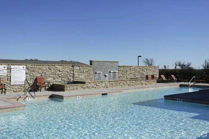 Refreshing swimming pool with stone water feature and surrounding sun deck at Arroyo Seco Villas in San Antonio, TX.