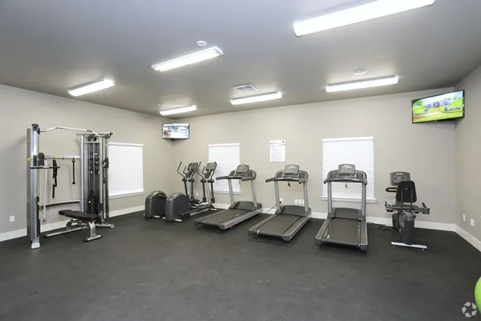 Cardio and strength training equipment in a spacious fitness center at Arroyo Seco Villas in San Antonio, TX.