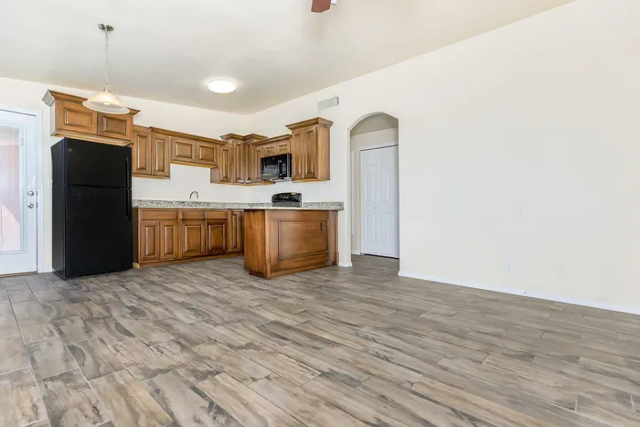 A modern kitchen with black appliances and an adjacent dining area with stylish seating at Bella Vista Place, El Paso, TX