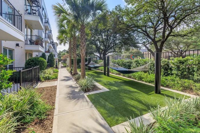 beautiful walking path with trimmed grass and is lined with hammocks surrounded by trees