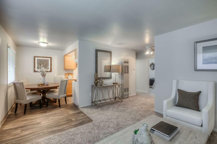 A bright and open living and dining room featuring a wooden dining table, elegant chairs, and cozy seating at Viewcrest Village in Bremerton, WA.