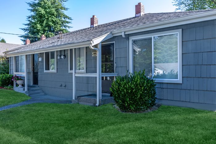 Close-up of an apartment entrance with windows, doors, and a landscaped yard at Viewcrest Village in Bremerton, WA.
