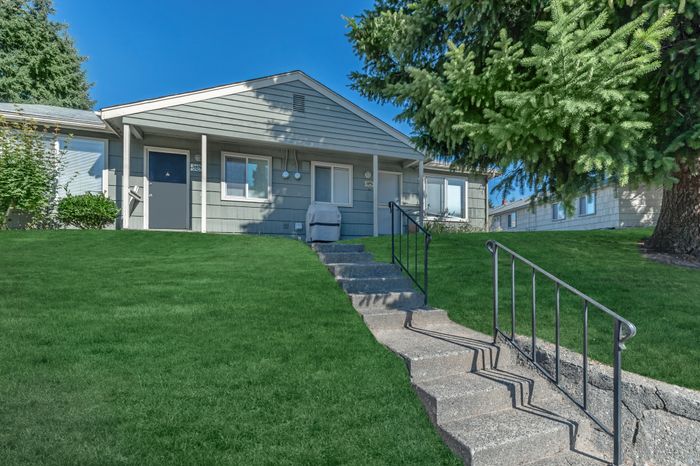 Front steps leading to a cozy apartment unit with well-kept lawns and tall trees at Viewcrest Village in Bremerton, WA.