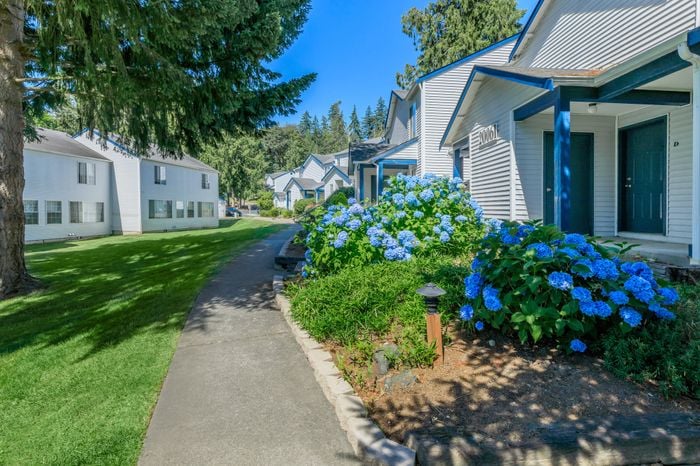 Well-manicured grounds with pathways, trees, and open green areas at Winton Woods Apartments in Poulsbo, WA.